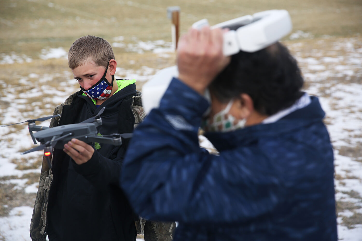 Quincy Ochs holds up the drone while teacher Rick Sanchez sets up the headset